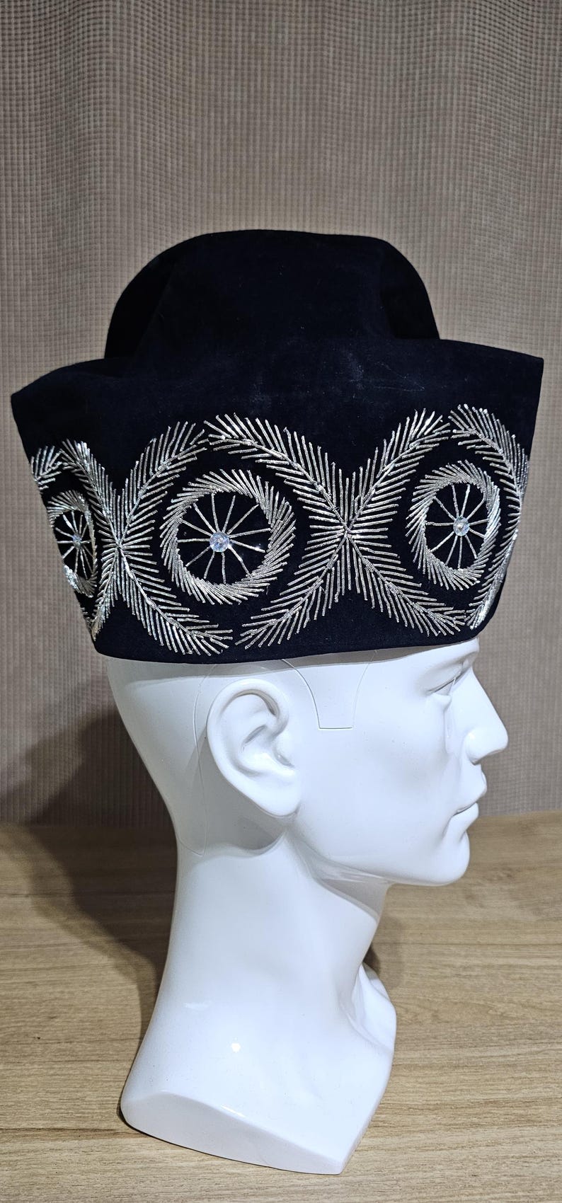 May include: A black velvet hat with a silver embroidered design. The hat has a wide brim and a rounded crown.