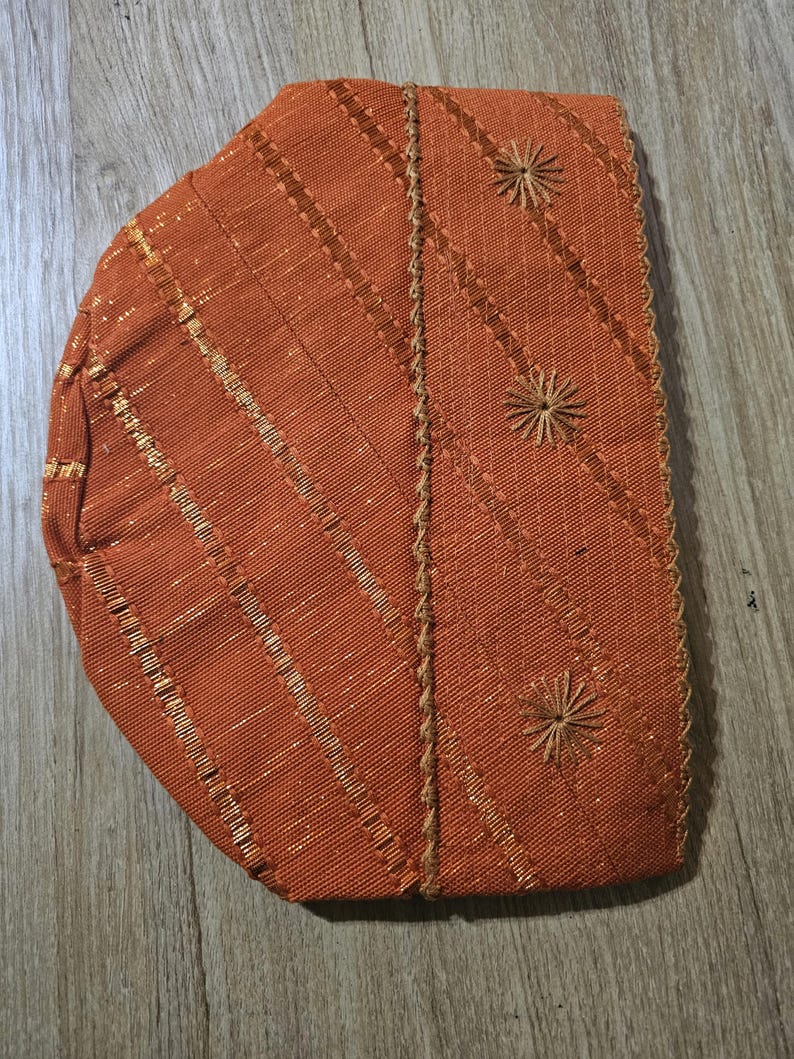 May include: A brown fabric hat with gold stitching and embroidered flower designs.