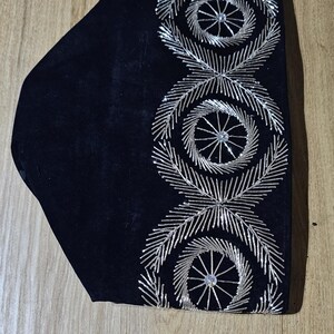 May include: A black velvet hat with silver embroidery. The embroidery features three circular designs with a central rhinestone.