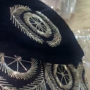 May include: A black velvet hat with silver embroidery. The embroidery features a circular design with a starburst pattern.