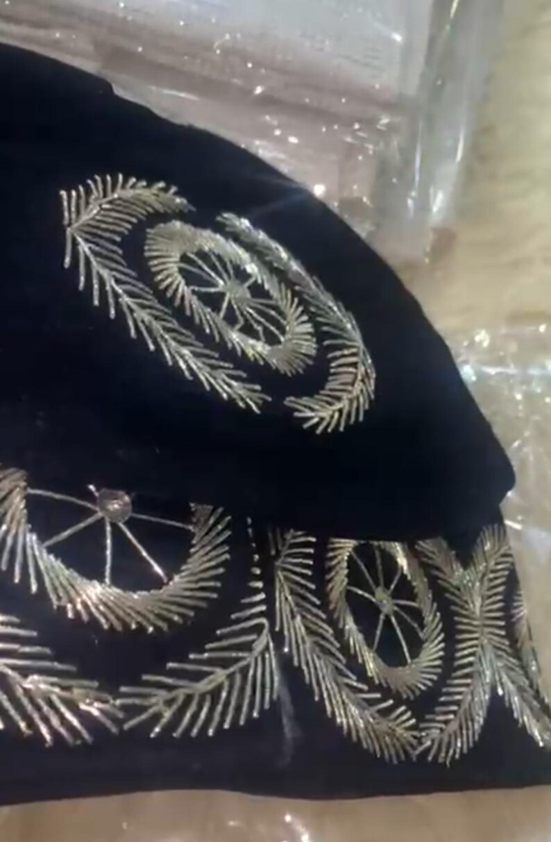 May include: A black velvet hat with silver embroidery. The embroidery features a circular design with a starburst pattern.