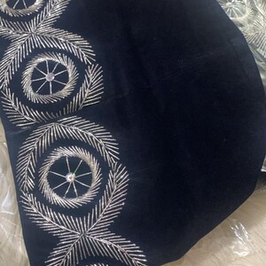 May include: A black velvet hat with silver embroidery. The embroidery features a circular design with a small rhinestone in the center.