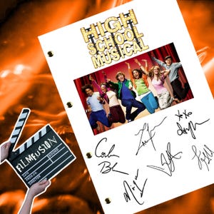 Könnte beinhalten: Ein weißes Drehbuch mit dem Titel "High School Musical" in goldenen Buchstaben. Das Drehbuch enthält ein Foto der Besetzung des Films, die in der Luft springt. Das Drehbuch ist von den Besetzungsmitgliedern signiert: Corbin Bleu, Zac Efron, Ashley Tisdale, Lucas Grabeel, Monique Coleman und Vanessa Hudgens.