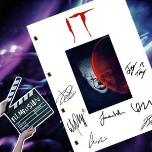 May include: A white script with the word "IT" in red, featuring a close-up image of Pennywise the Dancing Clown from the movie "IT". The script is signed by several people, including "Jay R. Fry" and "Jaunah Hill".