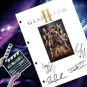 May include: A white script page for the movie "Gladiator II" with a photo of the cast and several autographs. The signatures include Russell Crowe, Paul Bettany, and Connie Nielsen.
