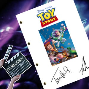 以下が含まれることがあります： 青い文字と黄色の文字で「トイ・ストーリー」というタイトルが書かれた白い紙。紙には、映画「トイ・ストーリー」のウッディとバズ・ライトイヤーの画像が載っている。紙にはトム・ハンクスのサインがある。