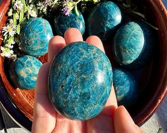 May include: A collection of seven smooth, teal blue, polished stones in a wooden bowl. The stones are various sizes and shapes, with a natural, marbled pattern.