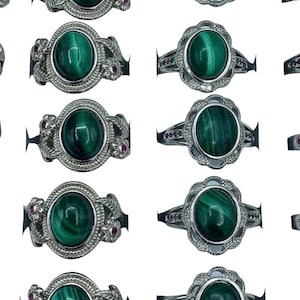 May include: A set of 10 silver rings featuring green malachite gemstones and pink accents. The rings have a floral design and are arranged in two rows of five.