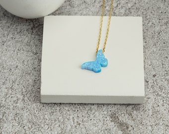 May include: A delicate gold chain necklace with a blue opal butterfly pendant.