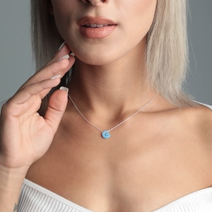 May include: A silver chain necklace with a light blue opal pendant in the shape of the letter G.