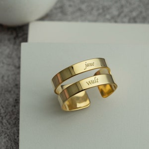 May include: Two gold metal bands with the names "Jane" and "Walt" engraved on them.