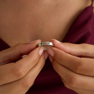 May include: A silver ring with a green gemstone and the name "Mark" engraved on the band.