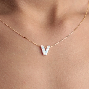 May include: A gold chain necklace with a white opal letter V pendant.
