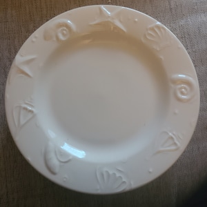 May include: White ceramic plate with a raised design of seashells and starfish around the rim.
