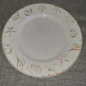 May include: White ceramic plate with a brown seashell design around the rim.
