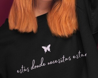 May include: Black sweatshirt with a white butterfly graphic and the text "estás donde necesitas estar" in white.