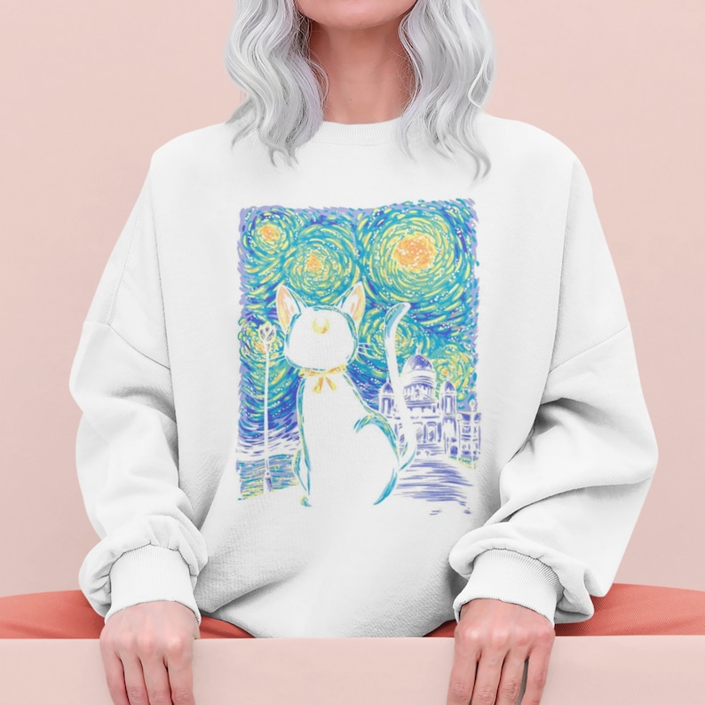 Pu&ograve; includere: Felpa bianca con una stampa grafica colorata di un gatto che guarda un cielo notturno stellato. La grafica ricorda la Notte Stellata di Vincent van Gogh.