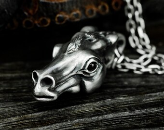 May include: A silver horse head pendant necklace with a detailed design and black eyes. The necklace is on a silver chain.