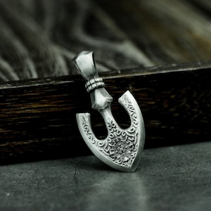 May include: Silver arrowhead pendant with intricate, detailed carvings. The arrowhead is a traditional symbol of strength and protection.