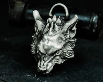 May include: A silver wolf head pendant with a detailed design. The pendant is made of metal and has a textured surface.