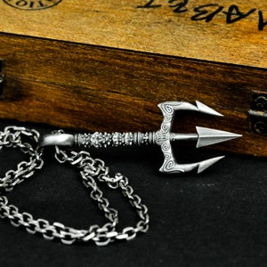May include: A silver trident necklace with a detailed design and a silver chain. The trident is a popular symbol of power and strength.