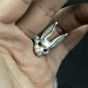 May include: A silver ring with a detailed rabbit design. The rabbit has black eyes and a textured surface.