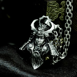 Puede incluir: Un colgante de plata que representa a un guerrero samur&aacute;i con un casco de drag&oacute;n. El colgante est&aacute; unido a una cadena de plata.