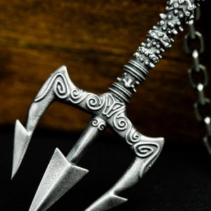 May include: A silver trident necklace with a detailed design and a chain. The trident has a textured surface and intricate swirls.