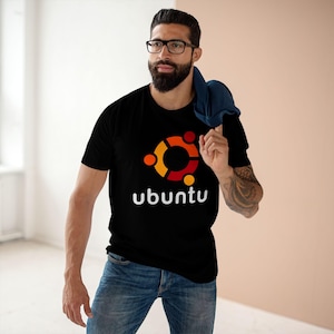 Peut inclure: T-shirt noir avec le logo Ubuntu en orange, jaune et rouge, et le mot "ubuntu" en blanc. Le t-shirt est porté avec un jean bleu.