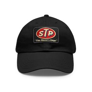 May include: Black baseball cap with a red, white, and blue STP logo patch. The patch has the text "The Racer's Edge" below the logo.