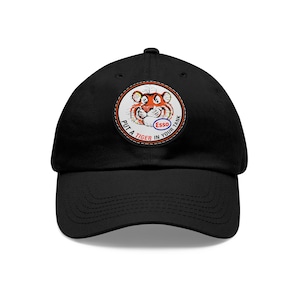May include: Black baseball cap with a white, red, and orange embroidered patch featuring a cartoon tiger and the text "Put a Tiger in Your Tank" and "Esso".