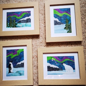 Op de afbeelding: Vier ingelijste afbeeldingen met een winterthema. Elke afbeelding toont een andere scène met een besneeuwd landschap, een ijsbeer, een pinguïn en een bos. De afbeeldingen zijn allemaal ingelijst in natuurlijk hout.