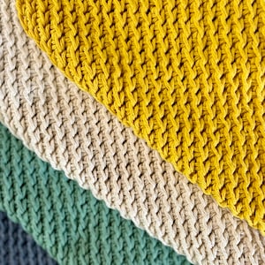 K&ouml;nnte beinhalten: Nahaufnahme eines mehrfarbigen geh&auml;kelten Stoffes mit einem gelben, beigen, gr&uuml;nen und grauen Muster.