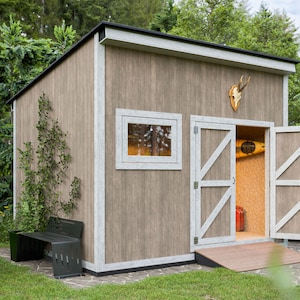 May include: A wooden shed with a black roof, white trim, and double doors. Inside, a kayak and a red container are visible. A deer antler mount hangs above the doors. A vehicle with a spare tyre is parked nearby.