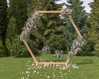 May include: A wooden hexagonal archway decorated with pink and white flowers, greenery, and candles. The archway is set up in a grassy area with trees in the background.