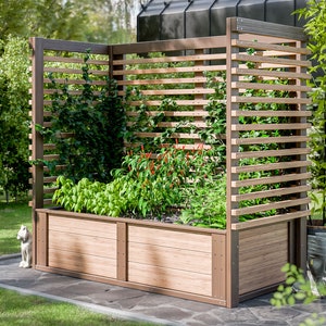 以下が含まれることがあります： トレリスと様々な植物が植えられた木製の高床式菜園。菜園は石畳のテラスと緑の芝生に囲まれています。