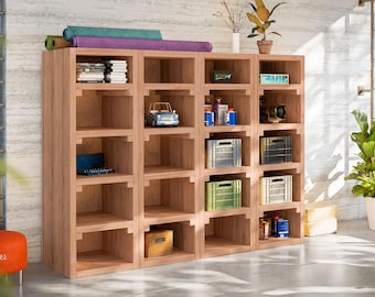 May include: A wooden shelving unit with multiple shelves and cubbies. The shelves are filled with various items, including books, toys, and storage containers. The unit is made of light brown wood and has a modern design.
