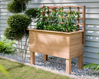 May include: A wooden raised garden bed with a trellis for growing plants. The bed is brown and has a natural wood finish. The trellis is made of wood and has a lattice design. The bed is sitting on four legs and is surrounded by white gravel.
