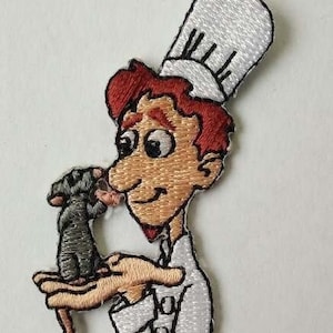 May include: Embroidered patch depicting a cartoon chef in a white uniform and toque, holding a small grey rat. The chef has red hair and a friendly expression. Ideal for clothing or accessories.