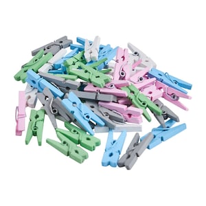 May include: A pile of small wooden clothespins in various pastel colors, including pink, blue, green, gray, and white. The clothespins are arranged in a random pattern, with some overlapping.