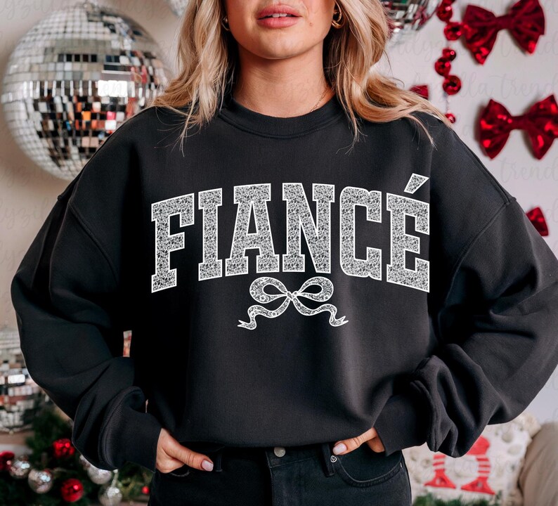 May include: Black sweatshirt with the word "FIANC&Eacute;" in white glitter letters with a white glitter bow underneath.