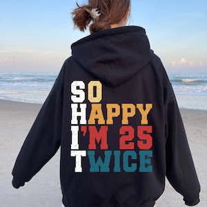 May include: Black hooded sweatshirt with a vintage-style graphic that reads "SO HAPPY I'M 25 TWICE".