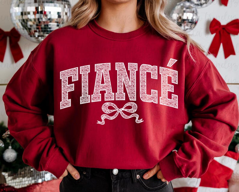 May include: Red sweatshirt with white text that says "FIANC&Eacute;" with a white bow underneath.