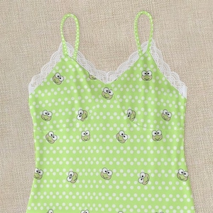 May include: Green and white pajama set with a frog print and lace trim. The top is a spaghetti strap tank top and the bottoms are shorts.