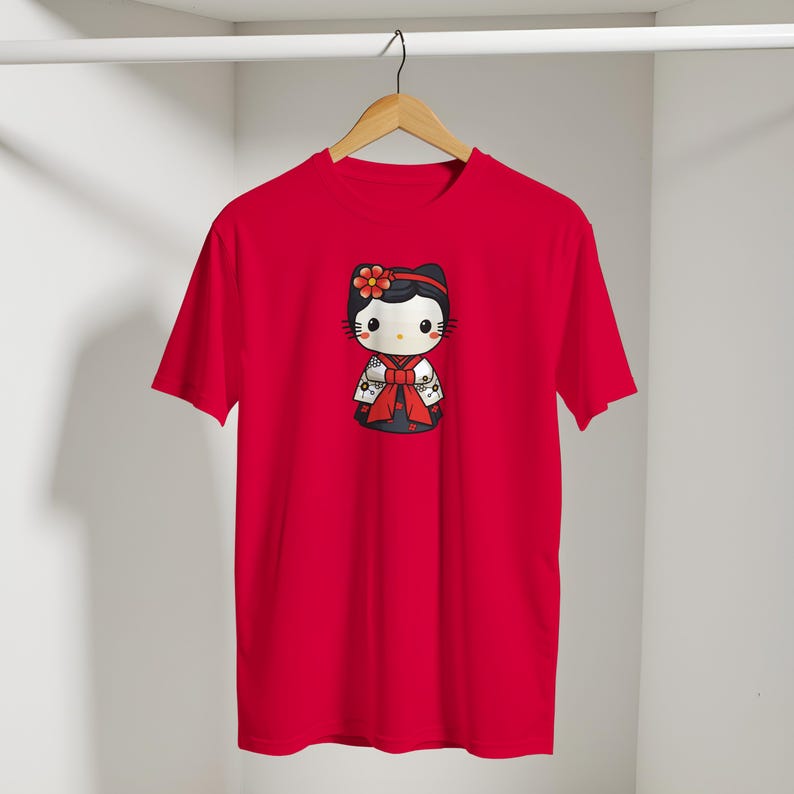 May include: A red t-shirt featuring a cartoon character in a kimono. The character has a black bow, a red flower, and a red bow. The shirt is hanging on a wooden hanger.
