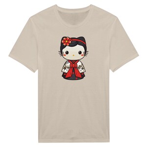 May include: Beige t-shirt featuring a cartoon character in a Japanese kimono. The character has a black head with a red flower, black whiskers, and a red and white kimono with a red bow. The t-shirt is a neutral color.
