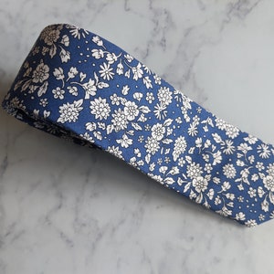 May include: A blue necktie with a white floral pattern.
