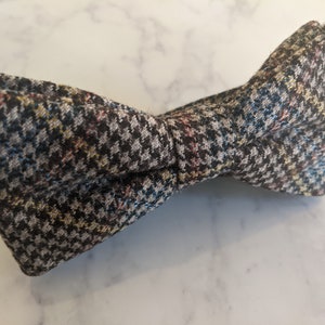 Op de afbeelding: Een bruine strik met een zwart, wit en blauw ruitpatroon.