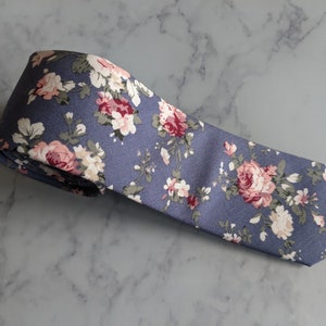 May include: A blue necktie with a floral pattern featuring pink and white roses.