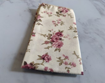 May include: A white fabric napkin with a pink and brown floral pattern.